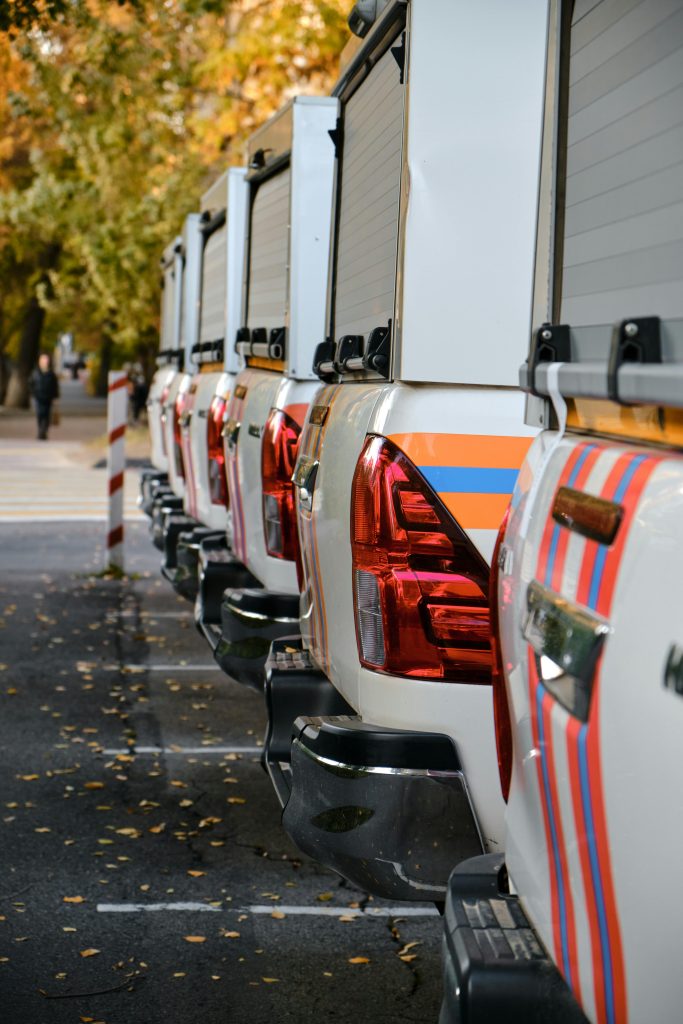 A row of pick-up trucks parked outdoors during autumn with falling leaves.